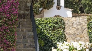 A stone building with a wooden staircase and a white wall with a bell tower. - House with pool, 20.000 m2 garden, ping-pong close to the beach for 18 people (Sant Andreu de Llavaneres)