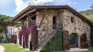 A stone building with a rustic design, featuring a stone staircase, wooden doors, and a covered porch. - House with pool, 20.000 m2 garden, ping-pong close to the beach for 18 people (Sant Andreu de Llavaneres)