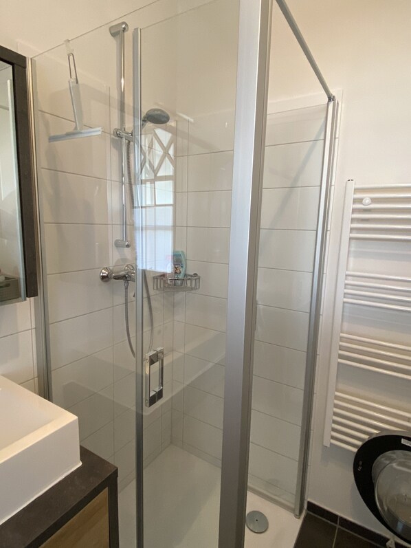 A modern bathroom with a glass-enclosed shower, a white sink, and a towel rack. - Apartment Landhaus (Fehmarn-Petersdorf) (Fehmarn)