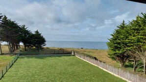 Un giardino erboso con vista sul mare, circondato da alberi e da un recinto.