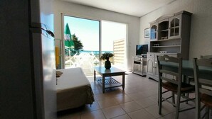Una camera con un letto, un tavolo da pranzo con sedie, una TV e un angolo cottura.
