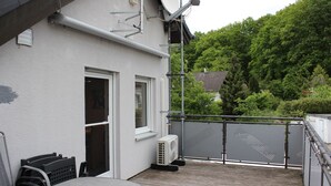 A balcony with a metal railing, a white building with a window, and a satellite dish.