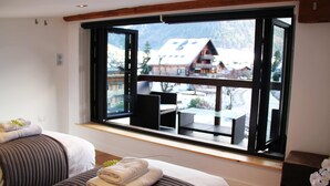 Ein Hotelzimmer mit großem Fenster, einem Bett mit Blick und einer Sitzecke mit Aussicht.