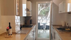 A modern kitchen with white cabinets, a central island, and a view to an outdoor patio. - One of the best located apartments in Conil.Sea views from every room. With WiFi (Conil de la Frontera)
