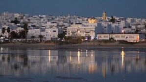 A coastal town with white buildings, a prominent church, and a calm body of water reflecting the structures. - One of the best located apartments in Conil.Sea views from every room. With WiFi (Conil de la Frontera)