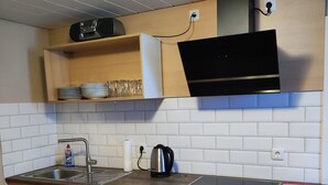 Una cucina moderna con mobili in legno, forno integrato, cappa aspirante in acciaio inossidabile e forno a microonde.