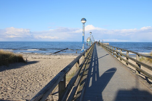 A wooden boardwalk leading to the beach with a clear view of the ocean and distant wind turbines. - Still available from 01.-12. May 2019 (Zingst (Ostseeheilbad))