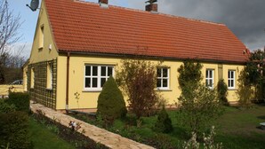 A yellow house with a red tiled roof, white windows, and a satellite dish. - beautiful garden with village idyll on the lagoon (usedom)