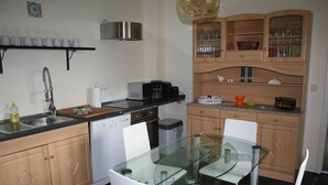 A modern kitchen with a glass dining table, white chairs, a coffee maker, and a microwave. - beautiful garden with village idyll on the lagoon (usedom)