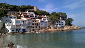 Un pueblo costero con edificios a lo largo del agua, una torre en una colina y cielos despejados.