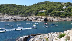 Una zona costera con barcos anclados cerca de costas rocosas y una ladera con edificios.