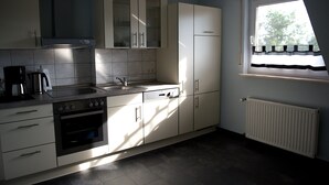 A modern kitchen with white cabinets, a stove, and a window with a view of trees. - spacious apartment in the countryside, ideal starting point for cycling (Rosendahl)