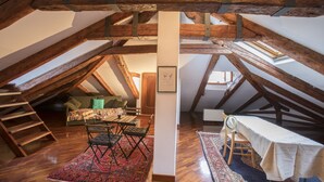 A loft bedroom with exposed wooden beams, a wooden staircase, a dining area with a table and chairs, and a bed with a white canopy. - Venetian Historic Residence at Rialto Market Square (Venezia)
