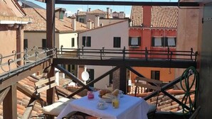 A rooftop terrace with a table set for breakfast, overlooking a cityscape. - Venetian Historic Residence at Rialto Market Square (Venezia)