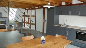 Una cucina moderna con mobili grigi, un tavolo da pranzo in legno e una scala che conduce a un altro piano.