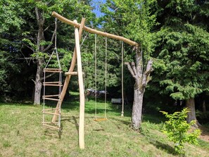 Relax in a serene park setting with a charming wooden swing set, featuring a central swing and two additional swings.