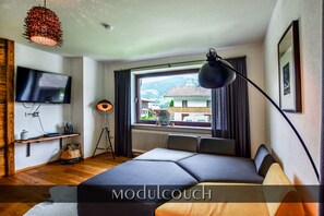 Quarto moderno com cama, televisão, janela com vista e luminária.