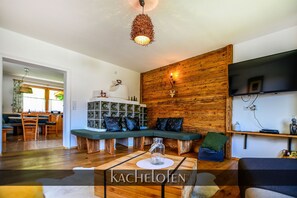 Uma sala de estar moderna com uma parede de destaque em madeira, um painel de entretenimento embutido e uma área de estar aconchegante.