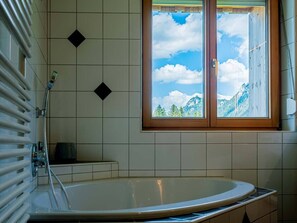 Ein Badezimmer mit Badewanne, einem Fenster mit Bergblick und einem Handtuchhalter.
