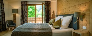 A bedroom with a bed, a chair, a nightstand, a lamp, and a window with curtains. - Alpine Chalet Vils in Tirol - on the Allgäu border - mountains, lakes, castles (Vils)