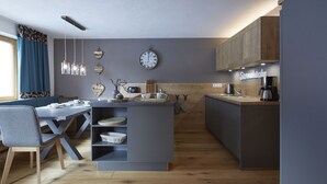 Una cucina moderna con isola centrale, mobili in legno e zona pranzo con una sedia e un tavolo blu.
