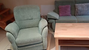 A living room with a light green armchair, a matching sofa, and a wooden coffee table.