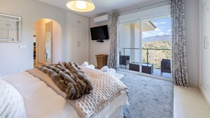 Ein Schlafzimmer mit einem großen Bett, einem Fernseher und einem Balkon mit Bergblick.
