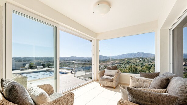 Ein geräumiger Balkon mit Korbmöbeln, großen Schiebegläsern und Blick auf den Pool.