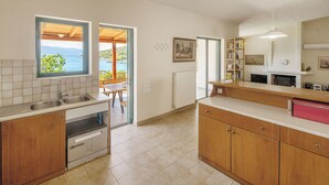 A kitchen with a view of the sea, wooden cabinets, a sink, and a dining area.
