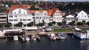 A waterfront hotel with multiple buildings, a dock with boats, and a café.
