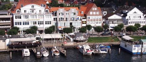 A waterfront hotel with multiple buildings, a dock with boats, and a café.
