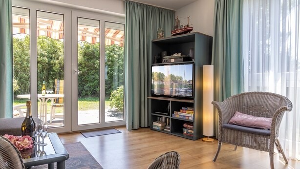 Een woonkamer met een televisie, een rieten stoel en een boekenkast.