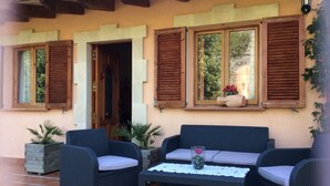 An outdoor seating area with wicker furniture and a table, a wooden door, and windows with shutters. - WIFI Villa with garden and private pool, near the town and beaches. Pollença (Pollença)
