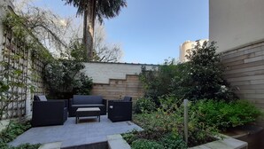 A patio area with outdoor furniture, a stone staircase, and a garden with various plants. - Superb character duplex in the European district (Ixelles)