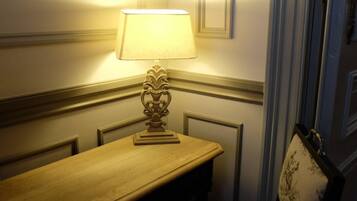 A corner room with a wooden table and a chair, a lamp on the table, and a door with a handle.