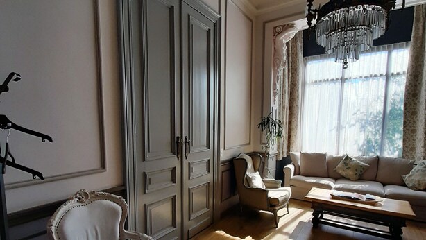 A room with a large wardrobe, a sofa, a chair, and a chandelier. - Superb character duplex in the European district (Ixelles)