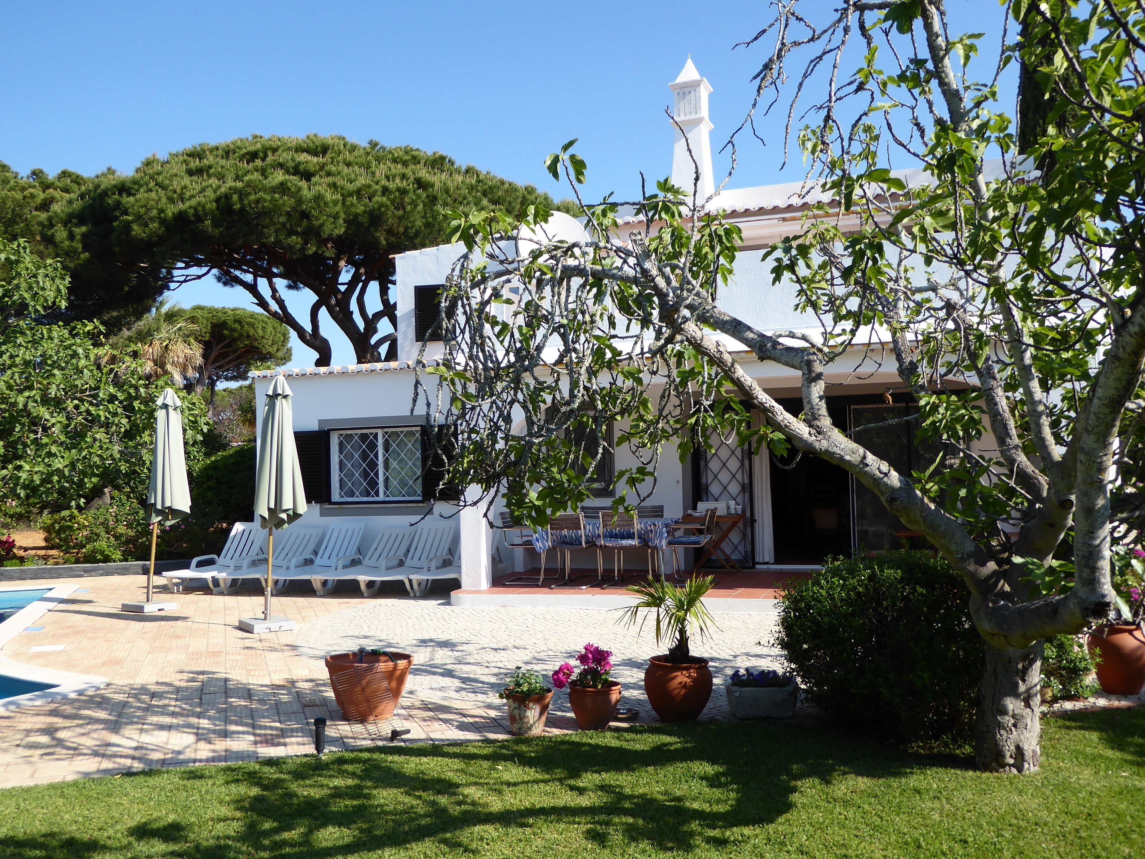 A villa with a pool, outdoor seating, and potted plants.