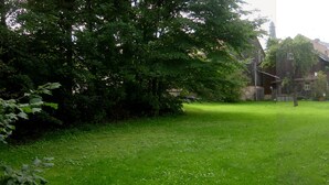 A grassy area with trees and a building in the background. - Historic farmhouse in rural village in northern Bavaria Landscape (Wunsiedel)