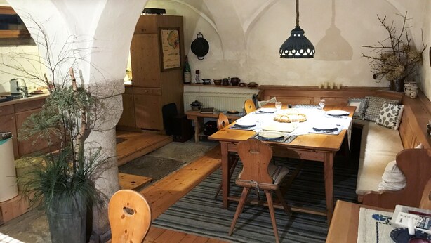 A cozy dining area with a wooden table set for four, a bench with cushions, and a hanging light fixture. - Historic farmhouse in rural village in northern Bavaria Landscape (Wunsiedel)