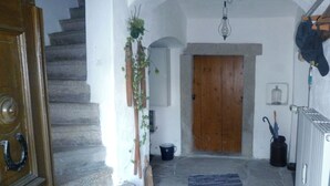 A staircase leading to a wooden door, a hanging plant, a radiator, and a black umbrella. - Historic farmhouse in rural village in northern Bavaria Landscape (Wunsiedel)