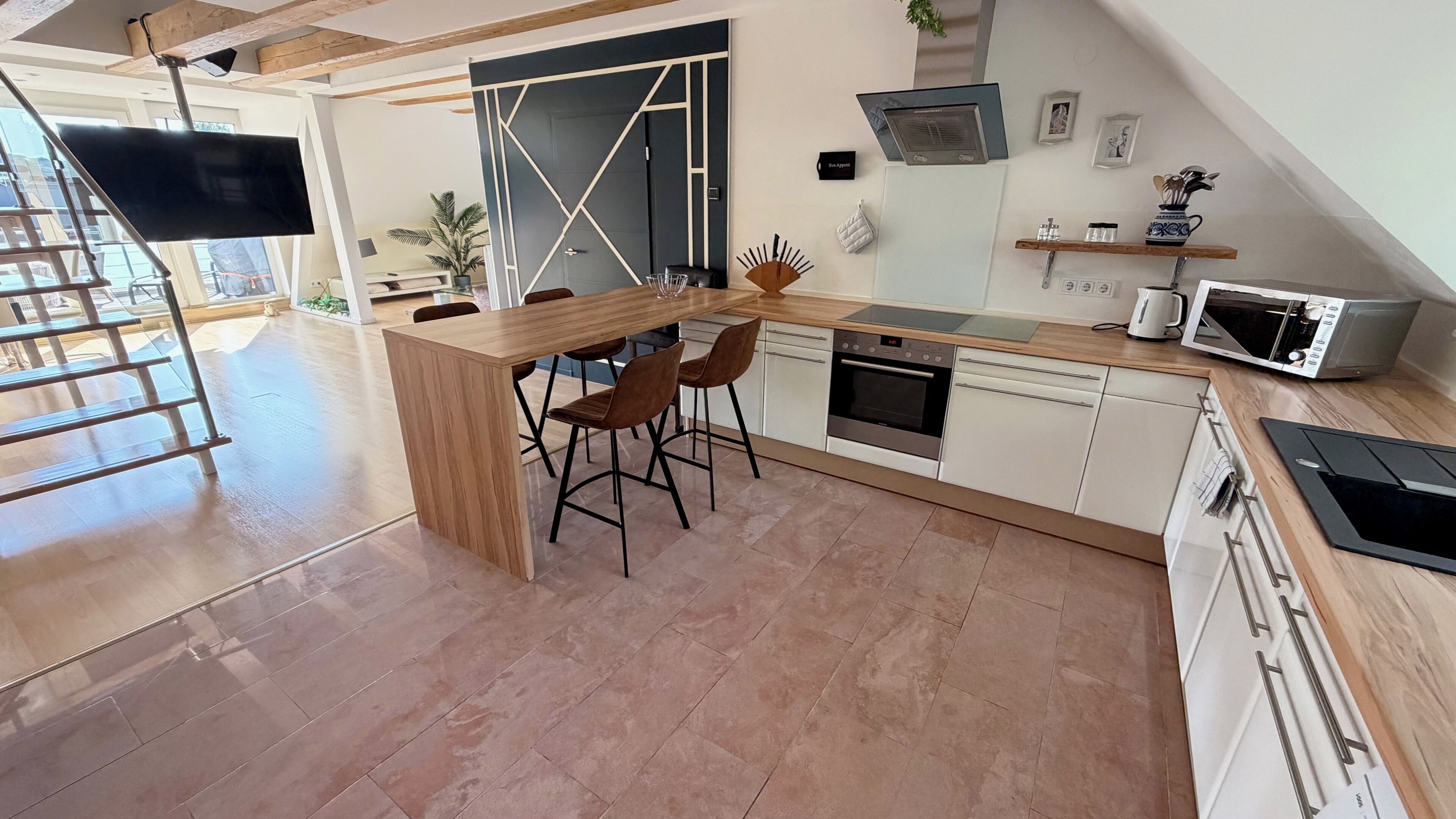 A modern kitchen with a central island, bar stools, a microwave, and a built-in oven.