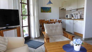 Cozy living space with a kitchenette, TV, sofa, dining table, and small kitchen area.