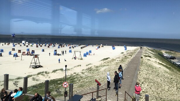 A beach with tents and people, a path along the shore, and a clear sky. - Modern, large 4 star house w/sauna and fireplace - 800m to the North Sea shore (Dornumersiel)