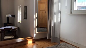 A room with a wooden floor, a dining table with chairs, a hanging lamp, a framed picture on the wall, and a window with curtains. - Idyllic apartment, central near the lake (Überlingen)