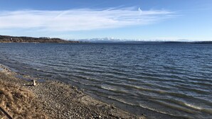 A calm lake with a rocky shoreline and distant mountains under a clear sky. - Idyllic apartment, central near the lake (Überlingen)