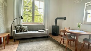 A cozy living room with a sofa, a table, chairs, a lamp, a fireplace, and a window with curtains. - Idyllic apartment, central near the lake (Überlingen)