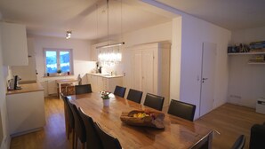 Een ruime eetruimte met een houten tafel, zwarte stoelen en een kroonluchter.