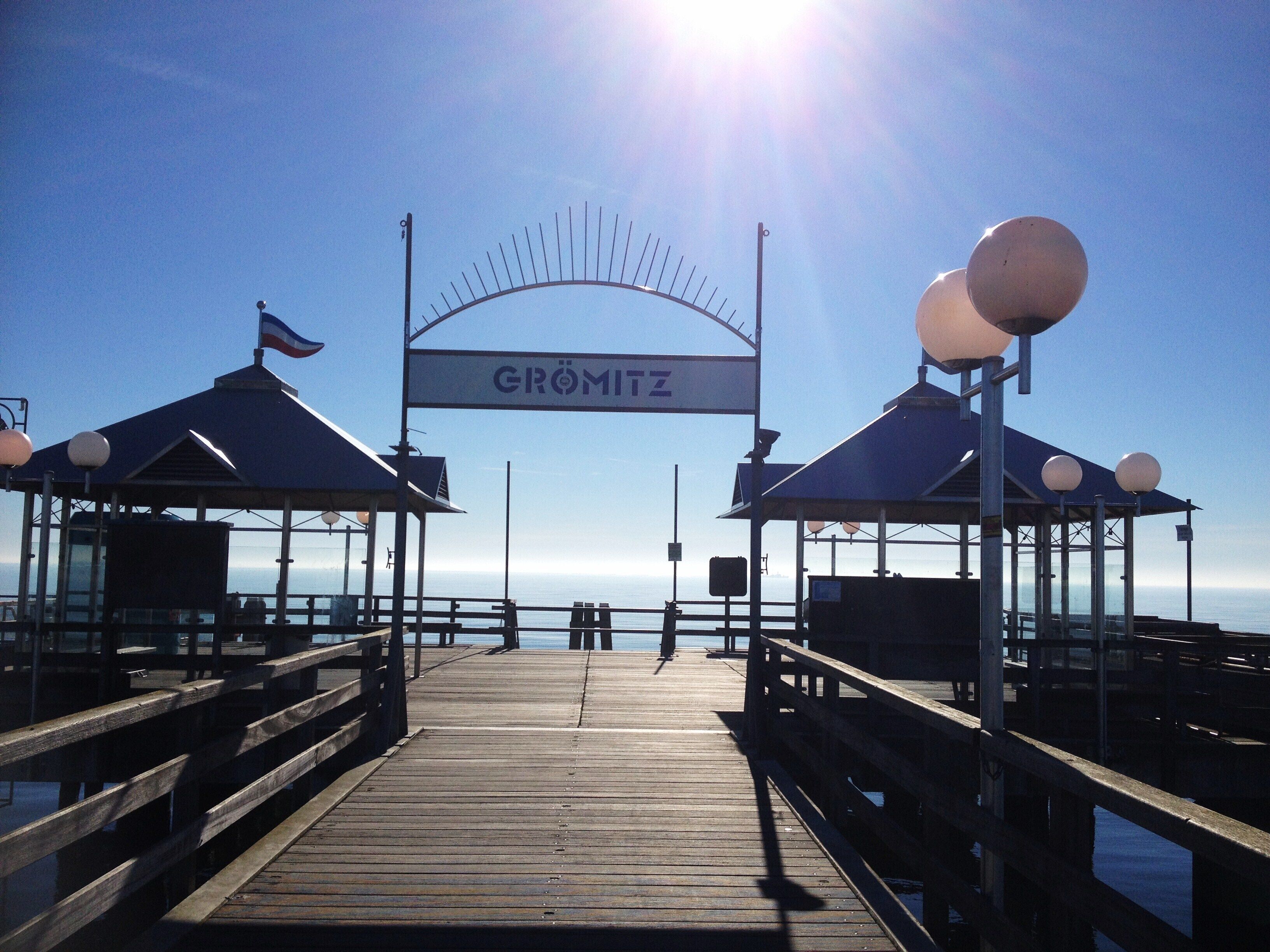 A wooden pier leading to a covered area with a sign reading "GRÖMITZ".