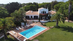Une grande maison avec une piscine, entourée de palmiers et dotée d’une pelouse bien entretenue.