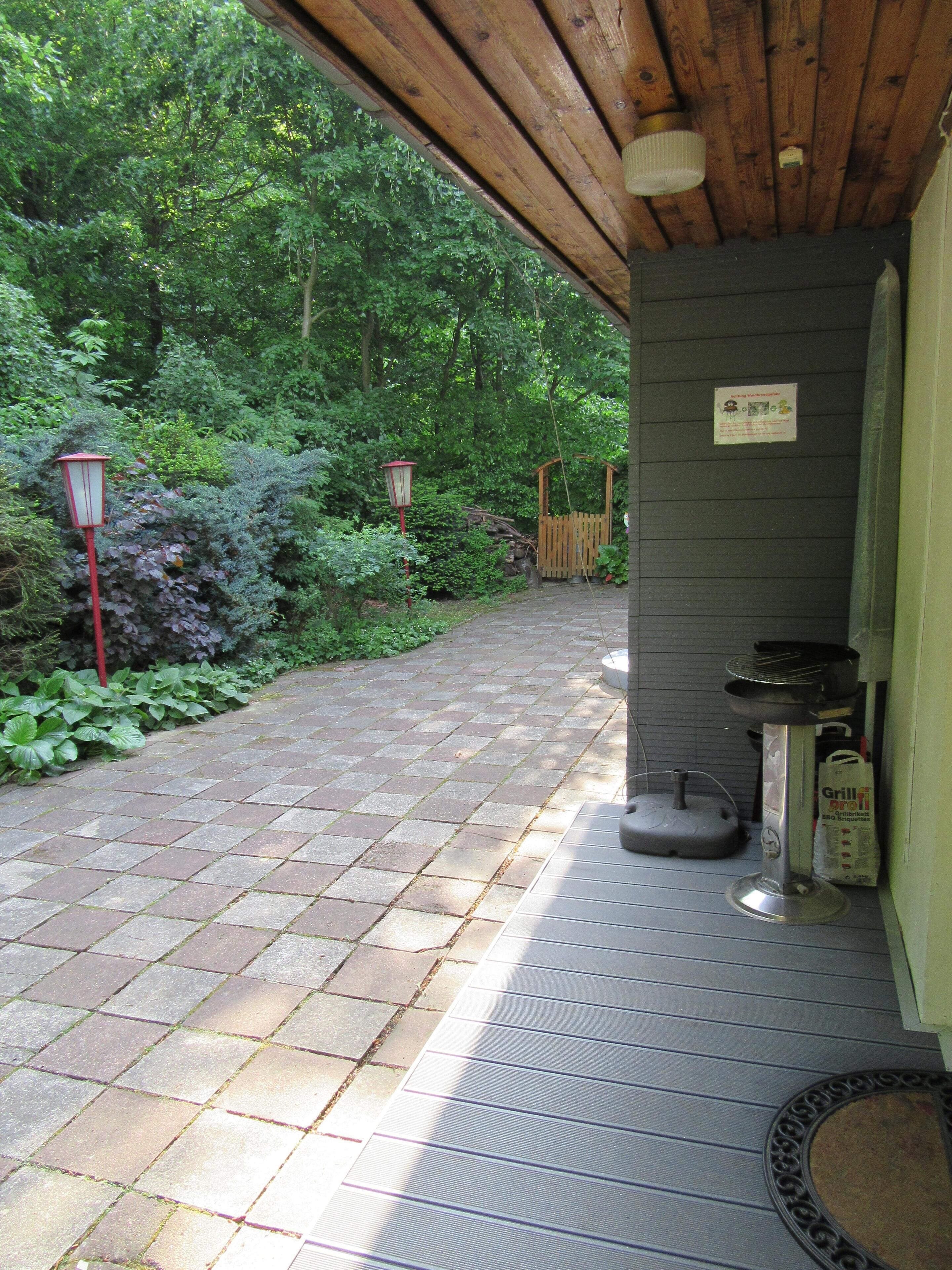 Un espace extérieur abrité, avec un chemin de pierre menant à une structure en bois.